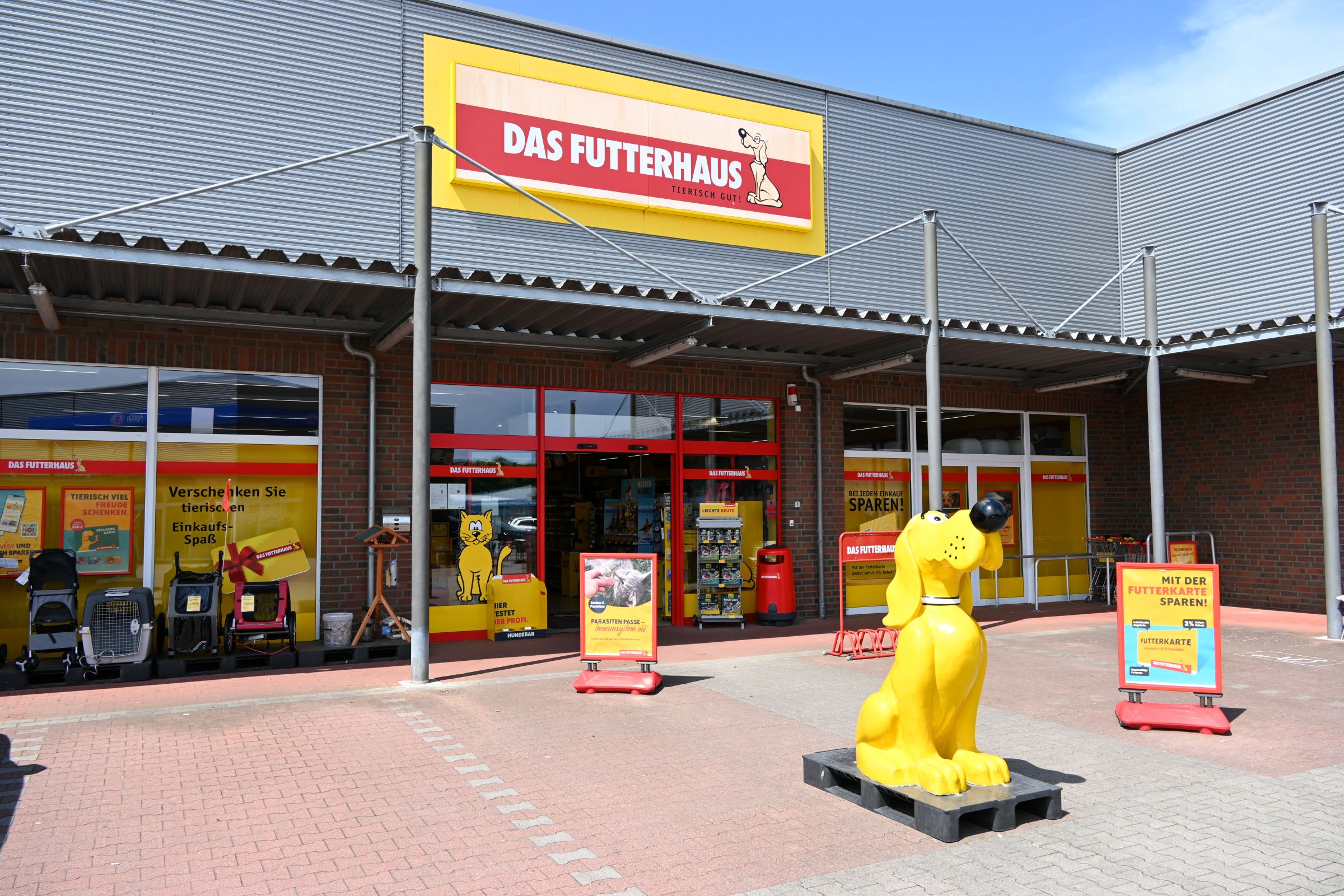 Eingang von DAS FUTTERHAUS Schortens mit gelbem Markenhund vor der Tür